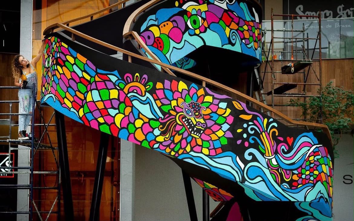 Latin Hands artist painting a large-scale spiral staircase mural