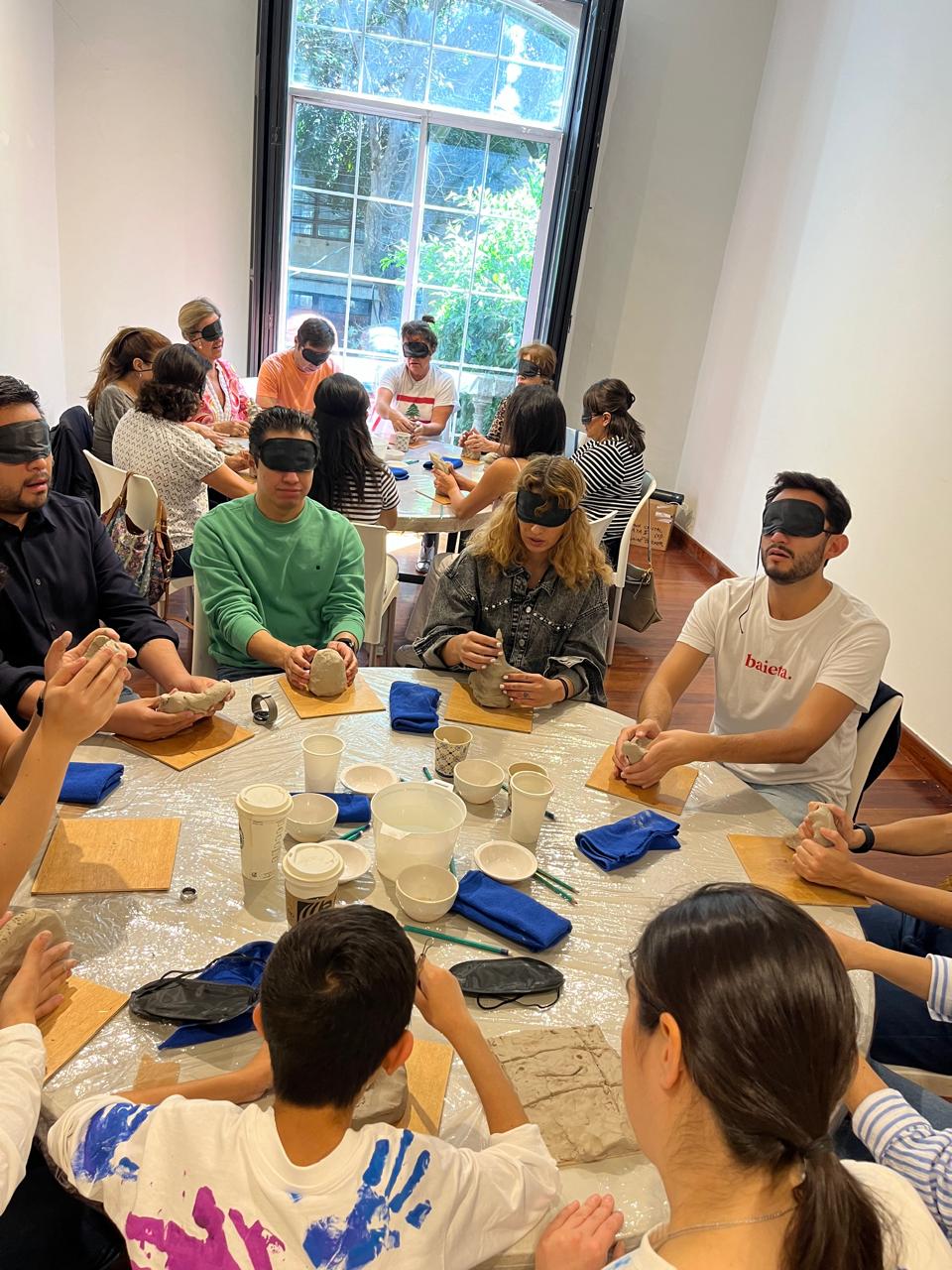 Participantes modelando arcilla con los ojos vendados en un taller