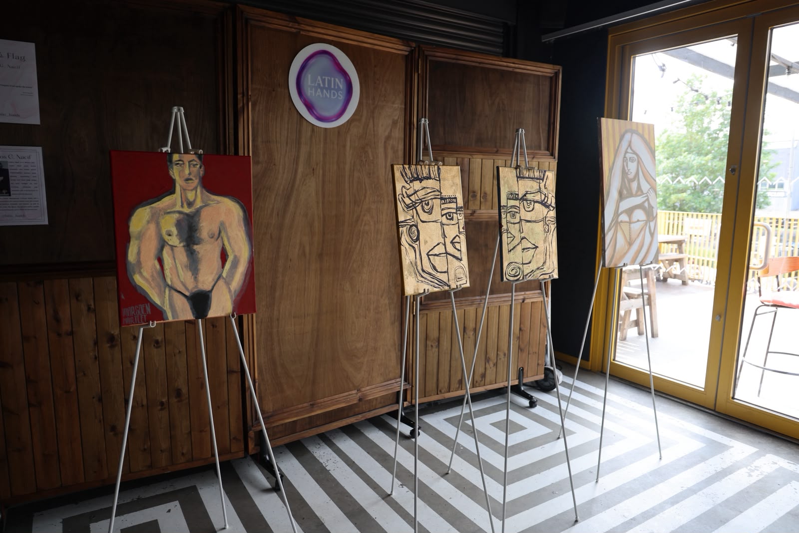 Paintings on easels at a Latin Hands exhibition